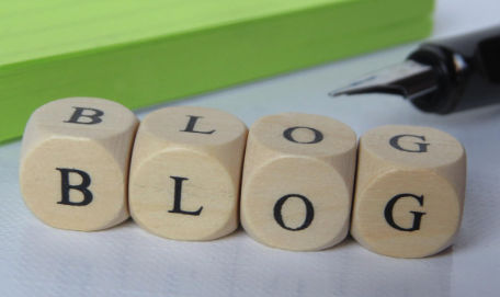 Wooden blocks spelling BLOG next to a fountain pen