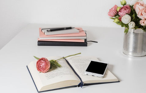 Calm creative desk with journal, phone, and flowers