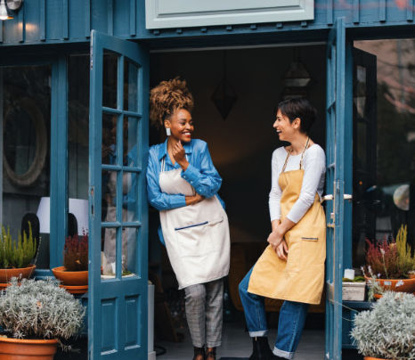 Two small business owners laughing together in their shop doorway